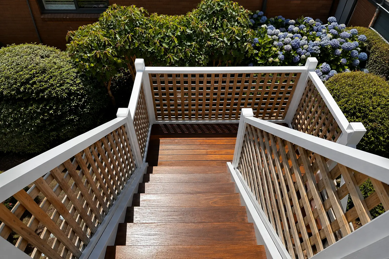 Outdoor timber stairs and landing with white handrails and surrounding garden.
