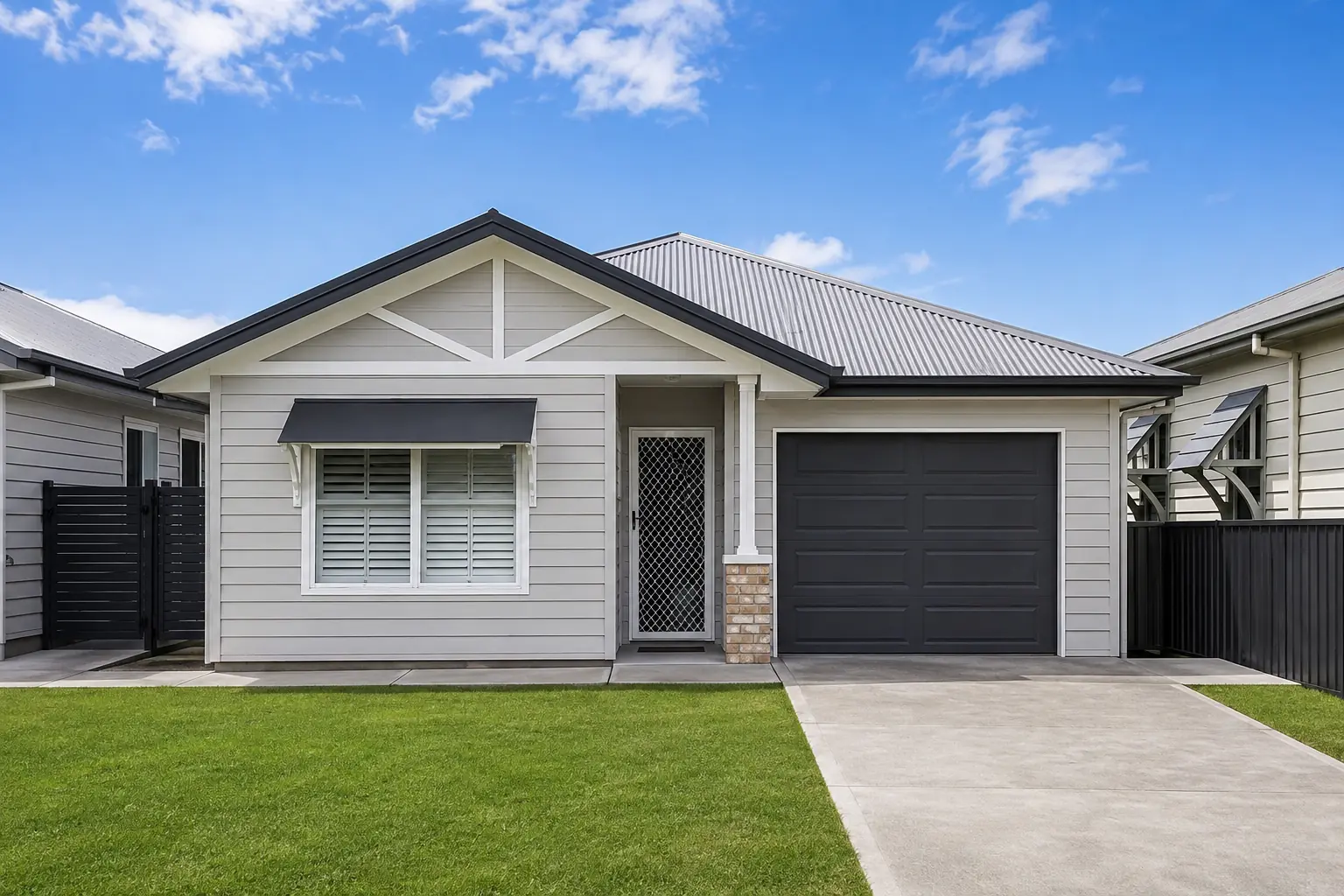 Grey single-storey house exterior with a dark roof and surrounding lawn.