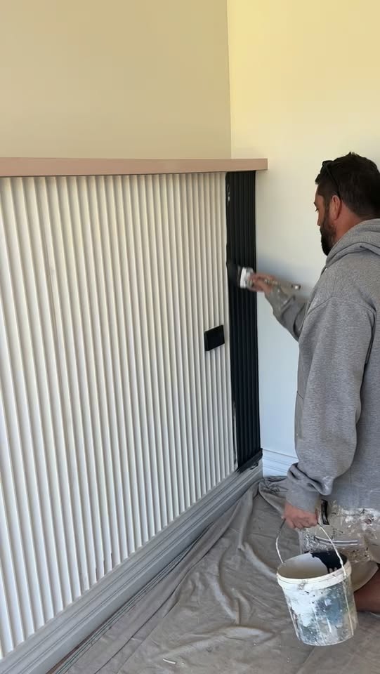 AdvaPaint applying a dark finish to fluted feature-wall panelling in a bedroom.