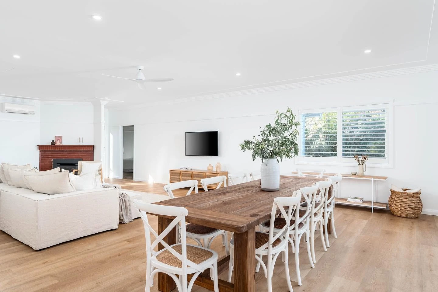 Interior room seen from the dining table, with white walls, cornices and timber trim.