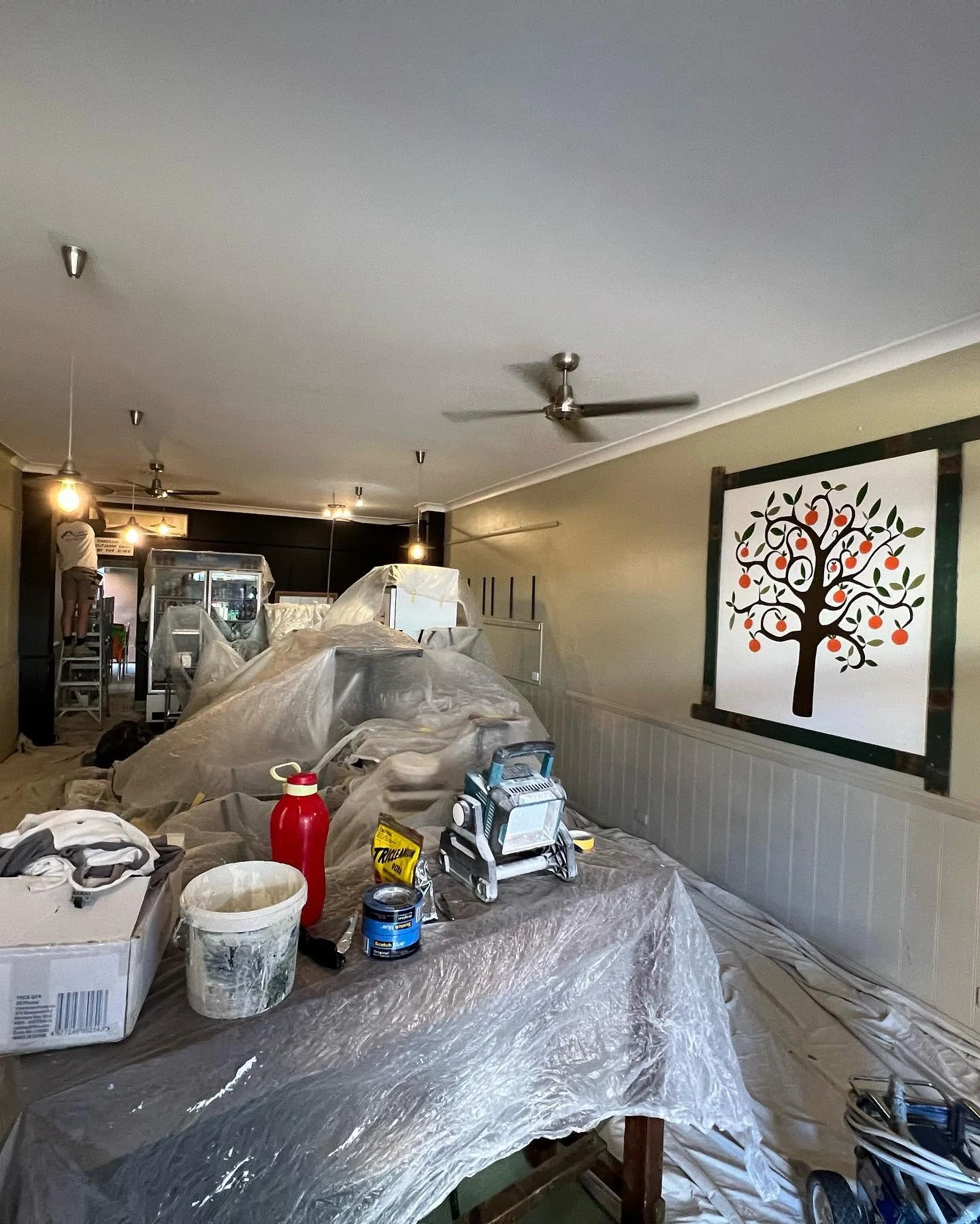 Interior furnishings and floor protected with sheeting, with paint tools ready for work.